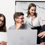 A team of four is smiling while working