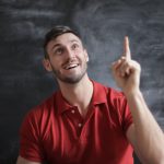 A man in a red shirt pointing his finger up